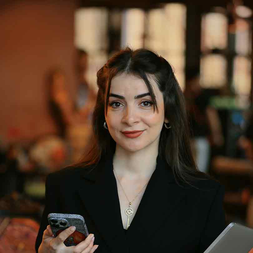 Portrait of Ashley wearing a formal black blazer holding a phone