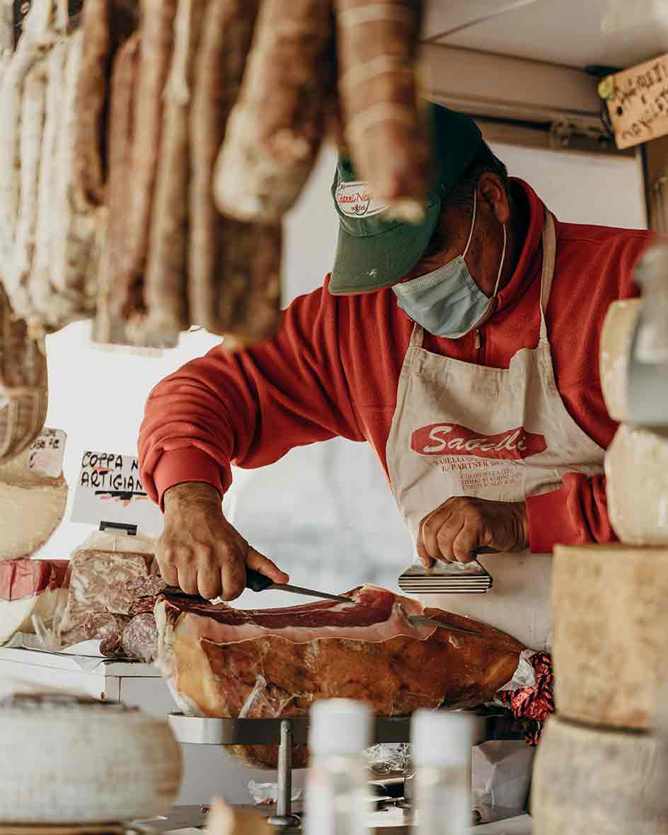 cheese shop worker cutting a piece of cheese