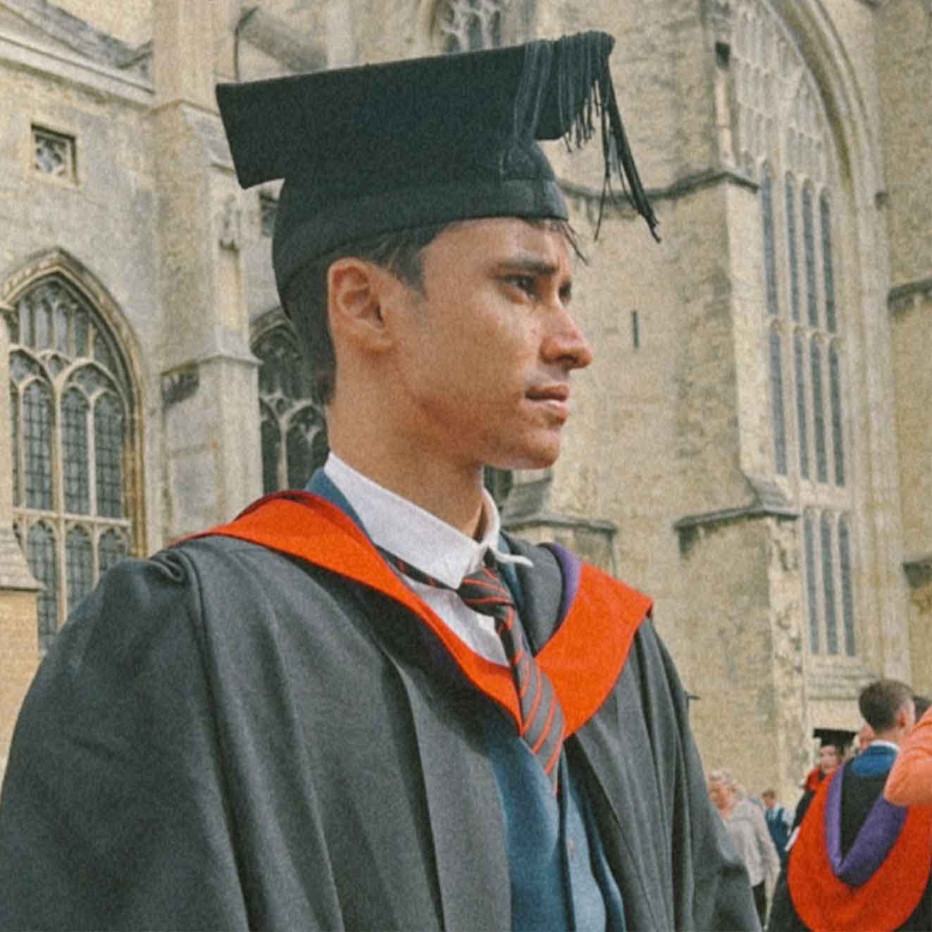 a man looking to the right wearing a graduation gown